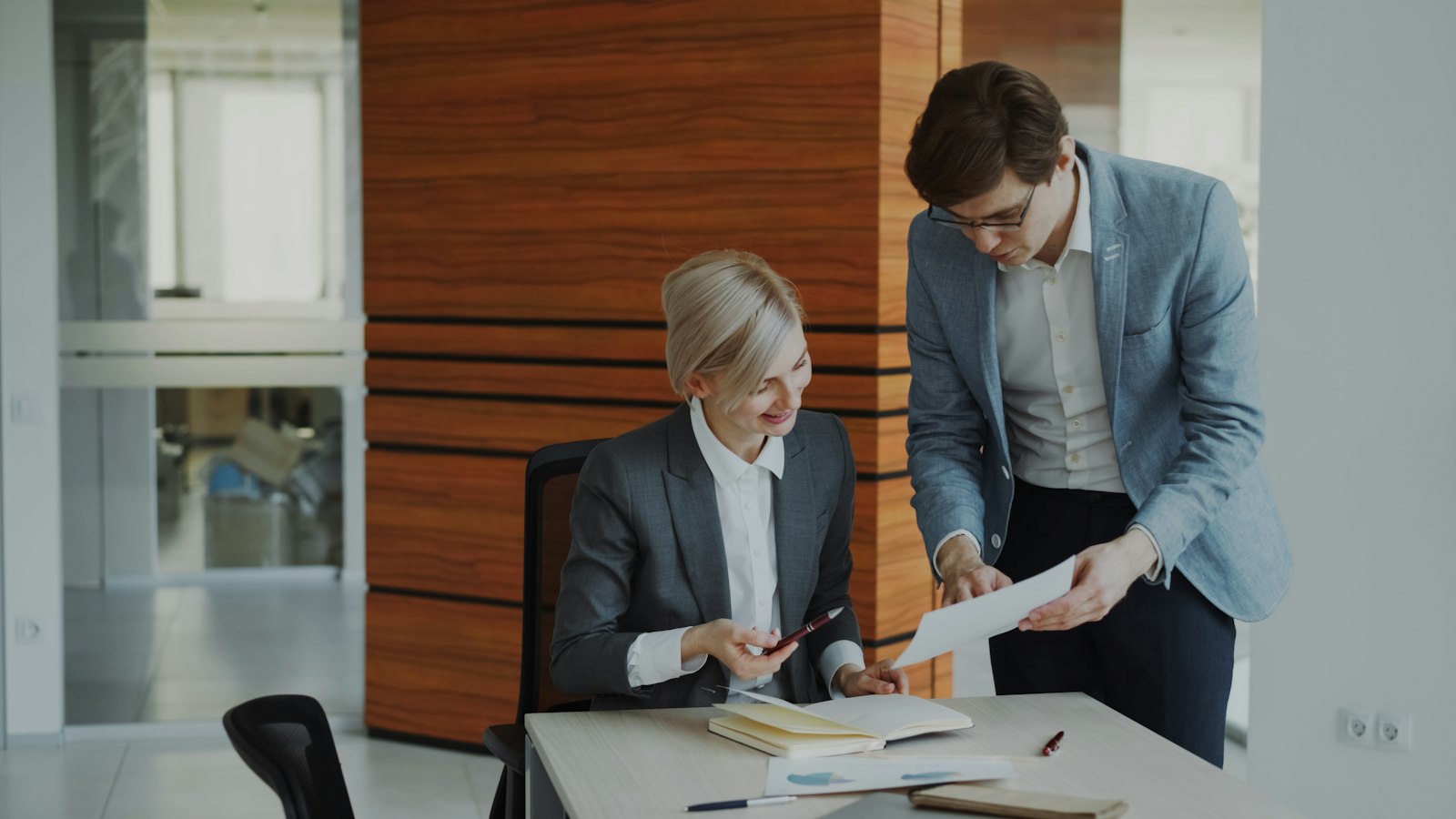 A controller and a credit manager reviewing an accounts receivable aging report together at an office desk